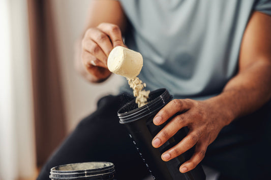 Mann füllt Proteinpulver in einen Becher.